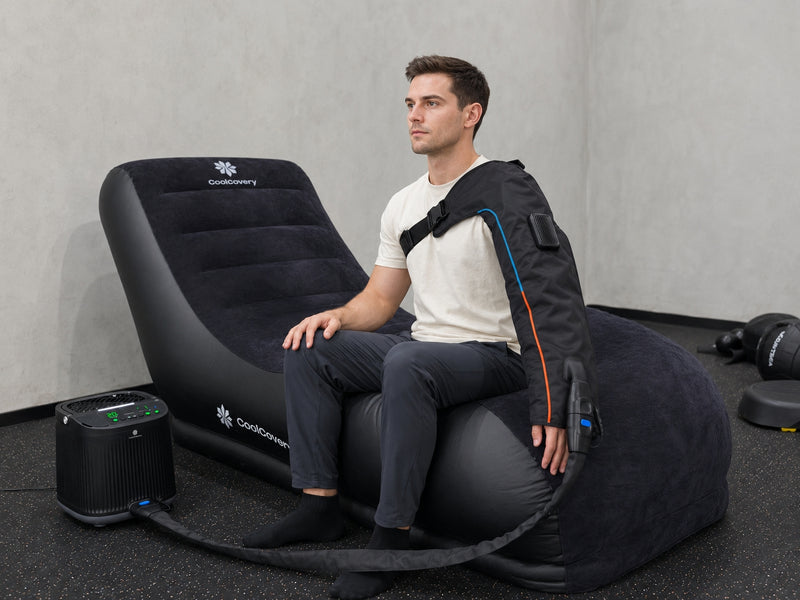 Man sit  on a compression sofa using coolcovery sleeve to recover his arm
